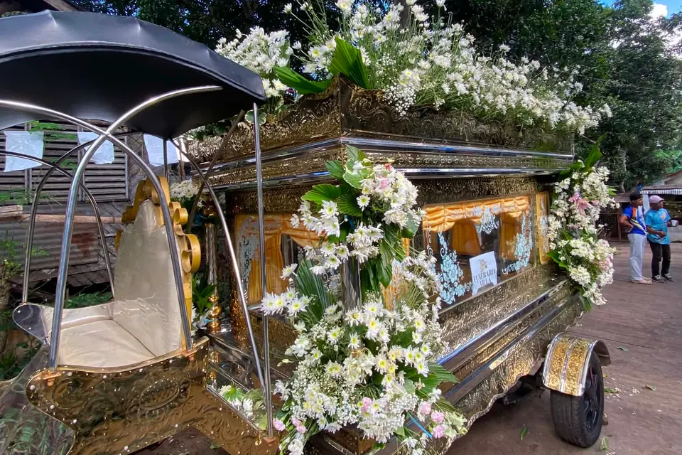 The office's funeral carriage (karwahe) with its gold casket compartment, black canopy and white flower decorations