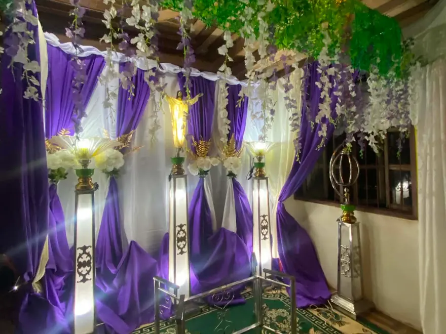 A prepared viewing alcove — purple and white drapes, hanging flowers and lit lamp stands