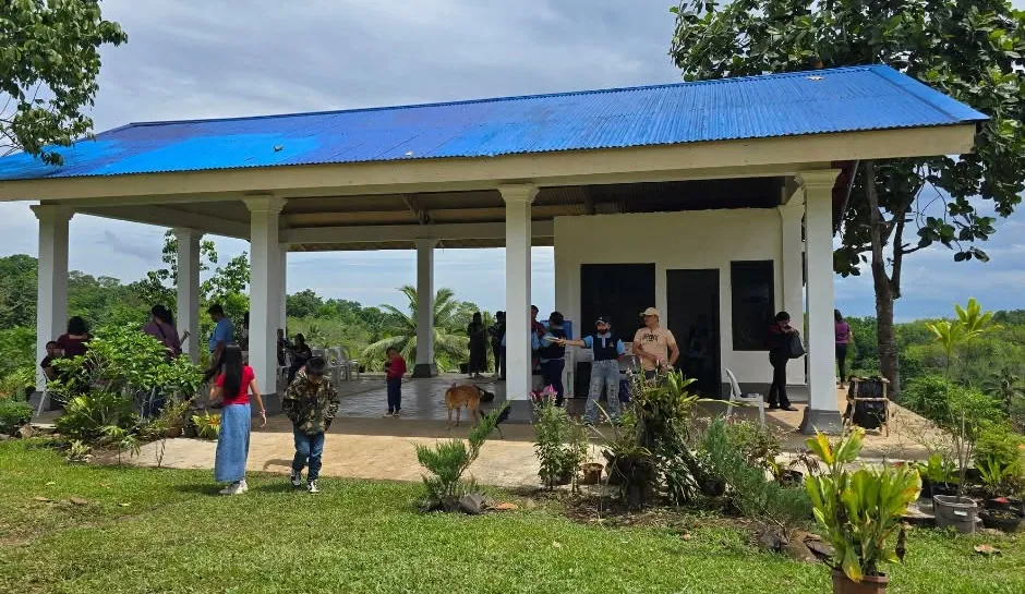 The park's open pavilion and lawn, with visitors on the tiled floor and green hills behind