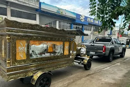 The client's sheet photograph of a funeral carriage on the street, with its gold-panelled casket compartment and glass window